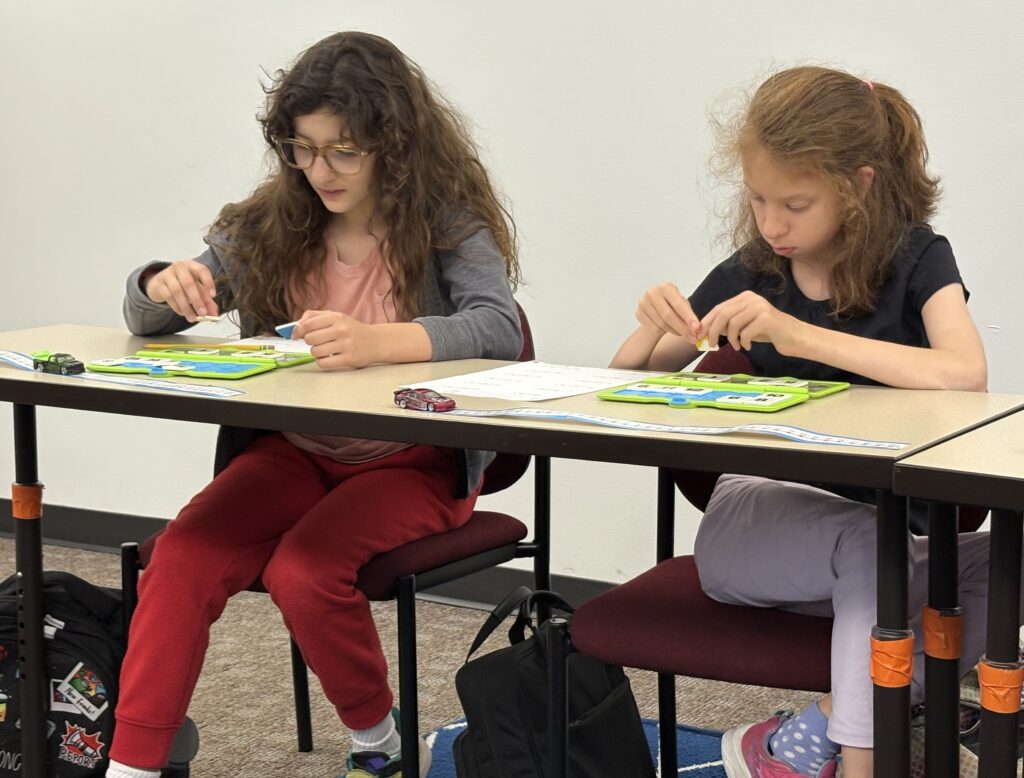 Two middle school students bend over manipulatives during Math class.