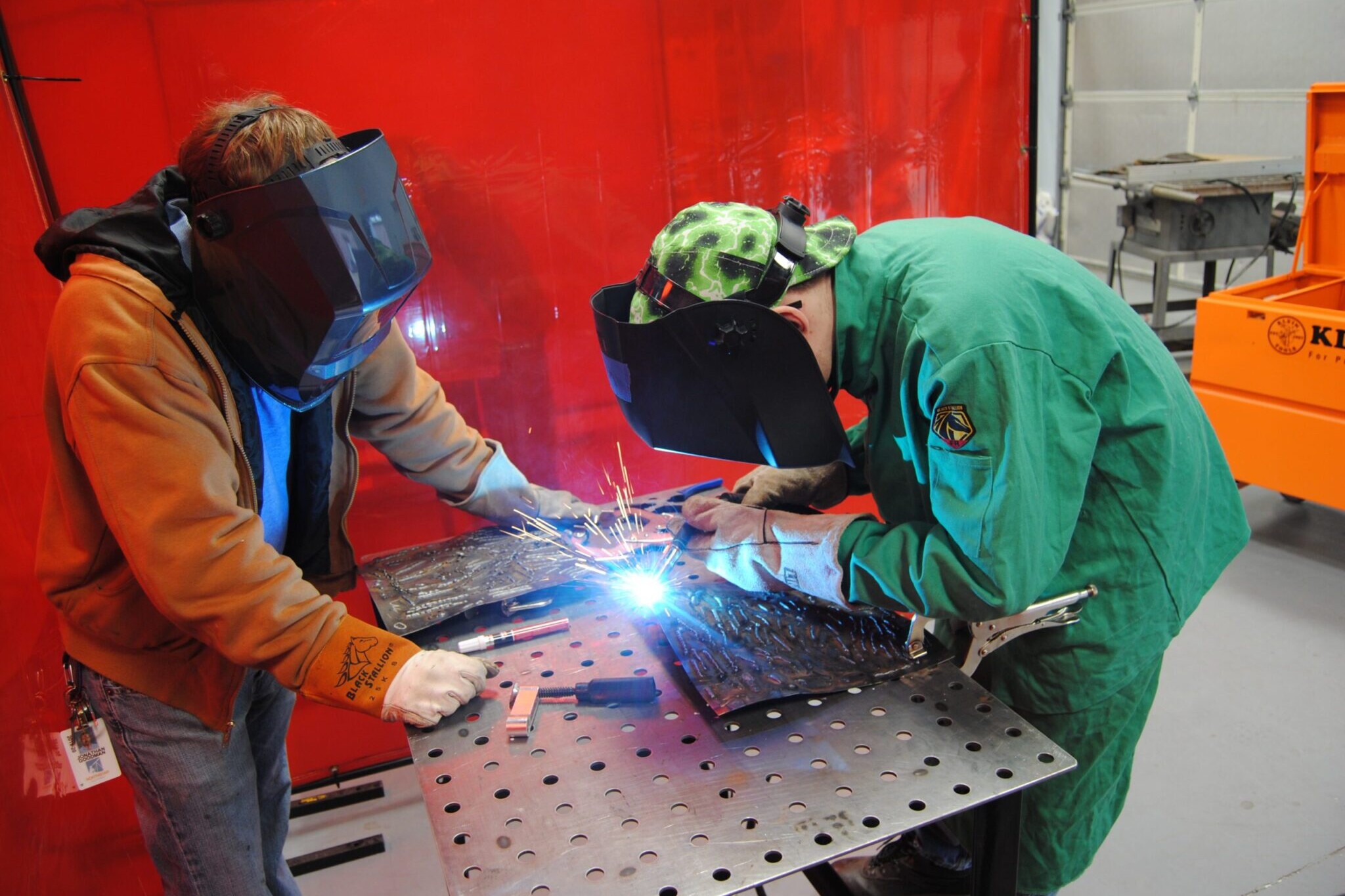 Career academy teacher assisting student with welding