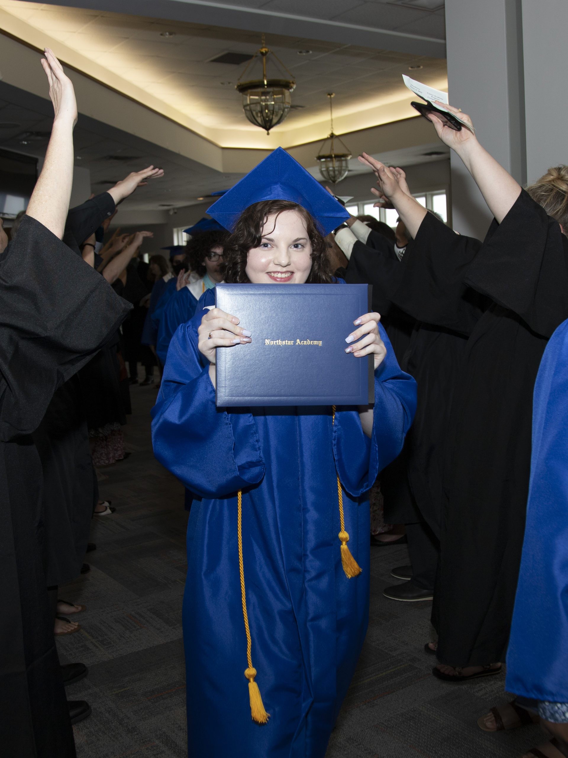 student smiling and holding up Northstar diploma