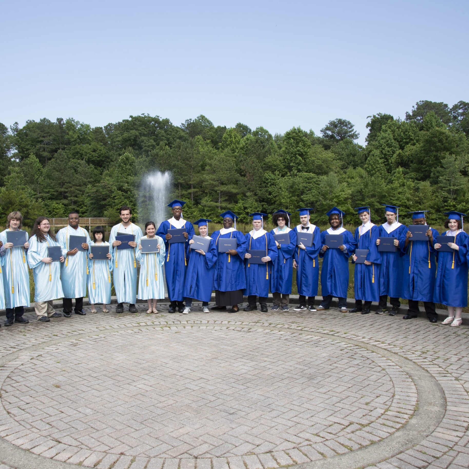 Group of Northstar graduates outside in front of water fountain holding diplomas