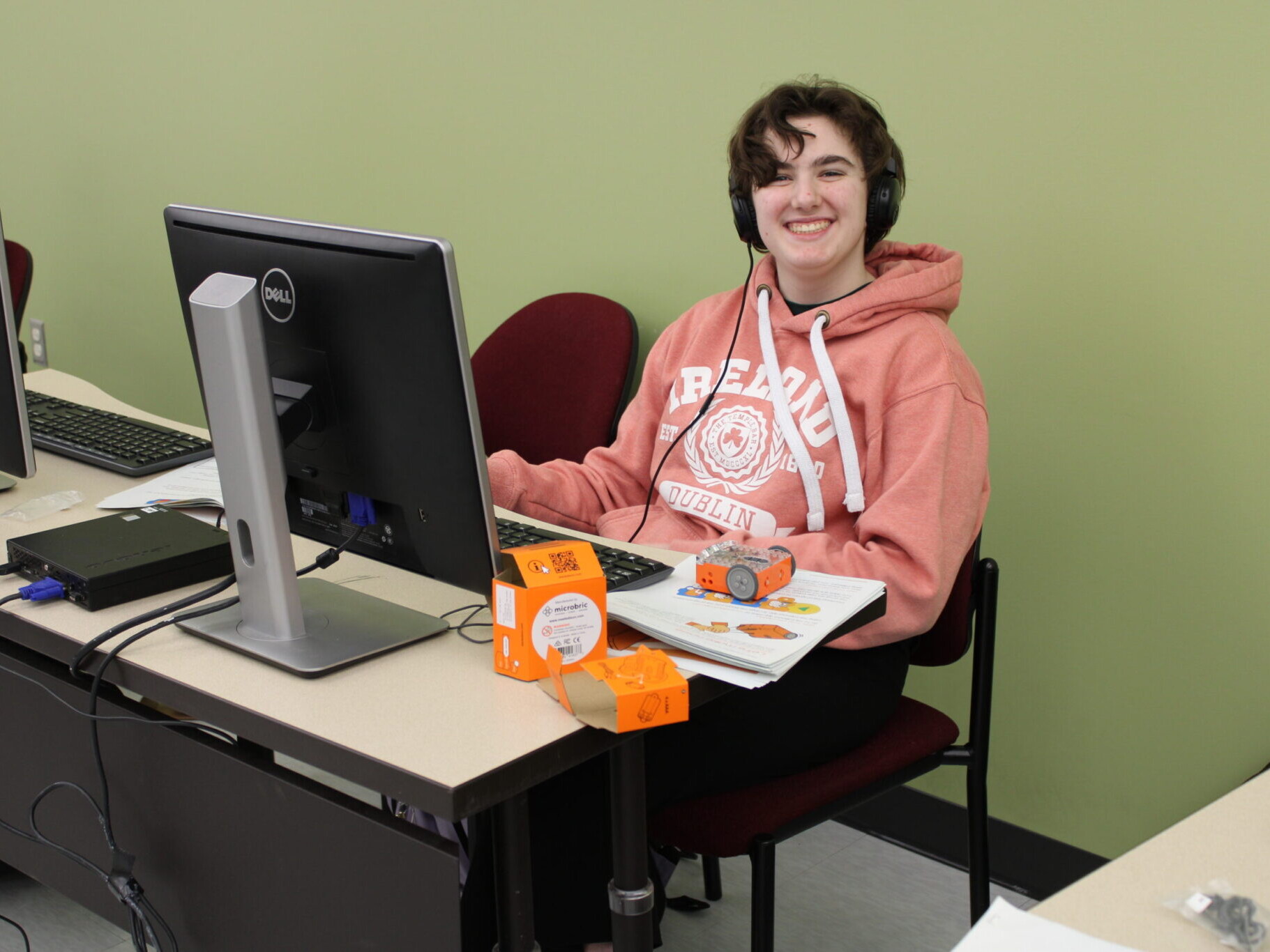 Student on computer smiling while programming robot