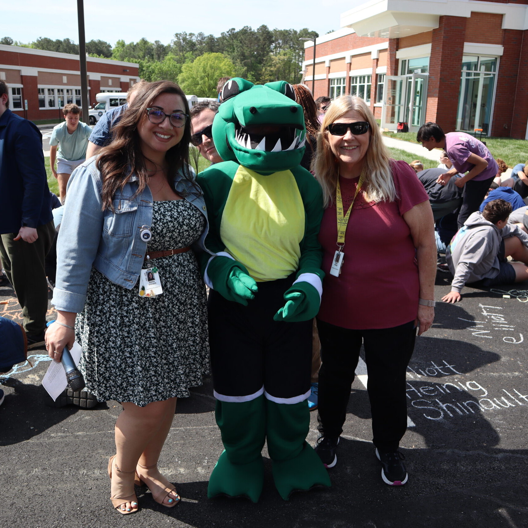 Two teachers smile with Navi the Gator.