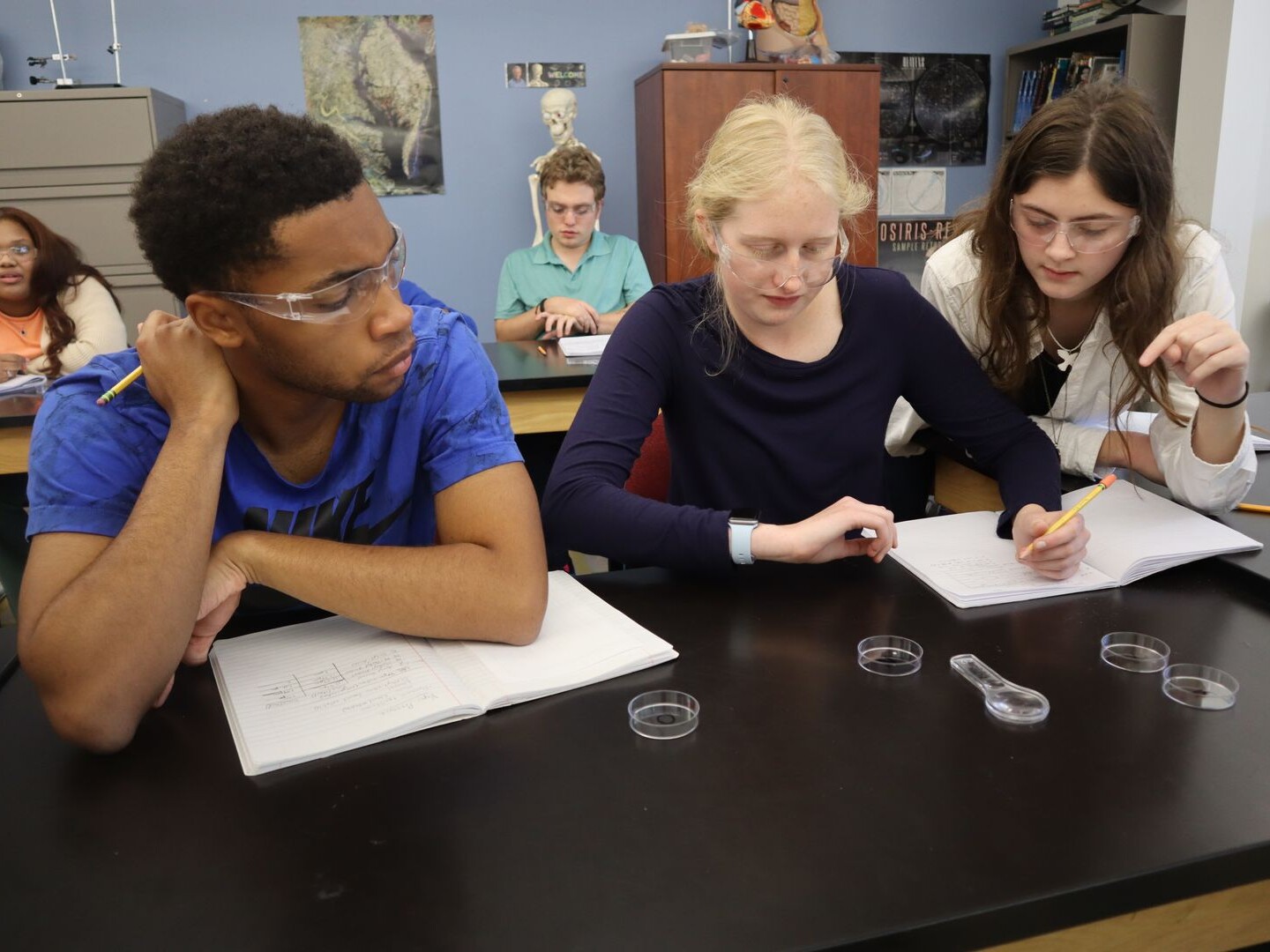 Three upper school students observe an experiment in science class.