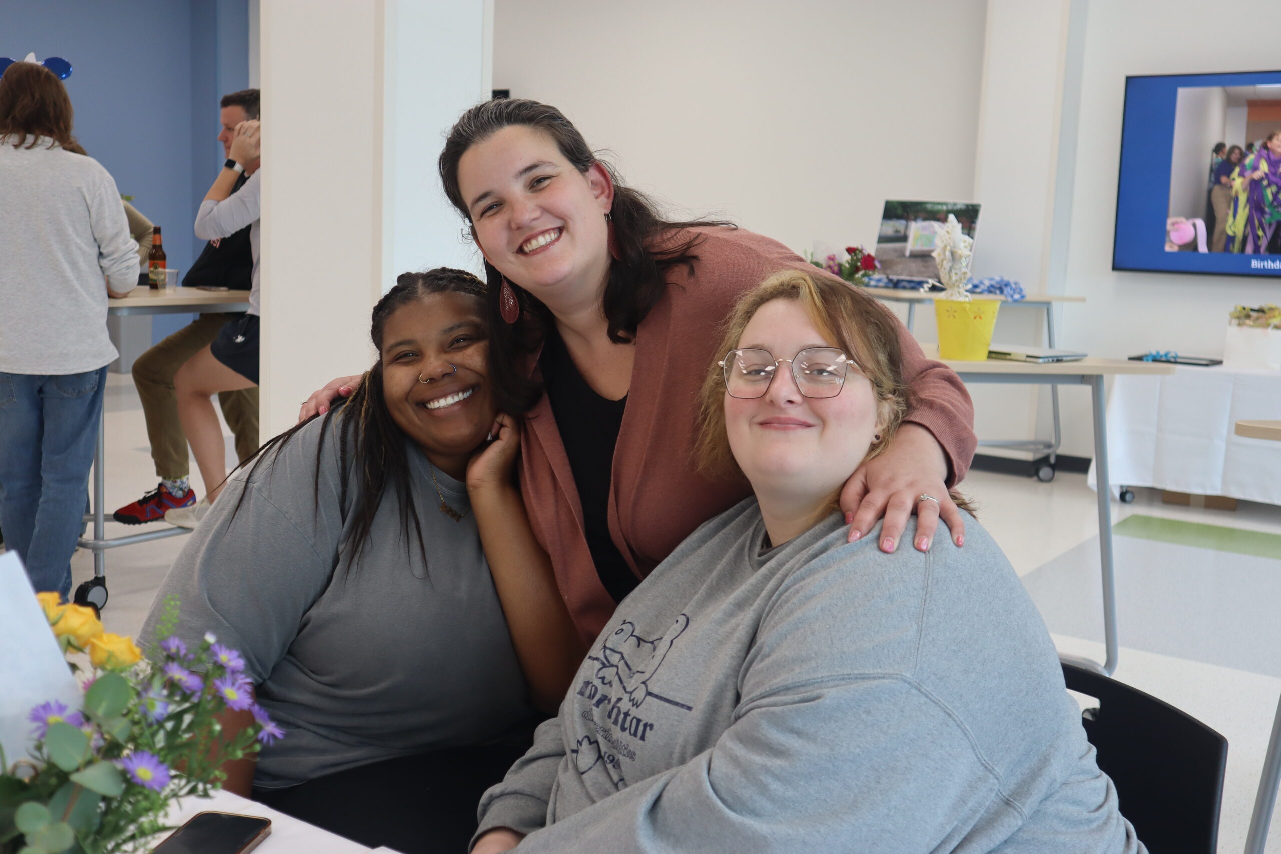 Three staff members hug.