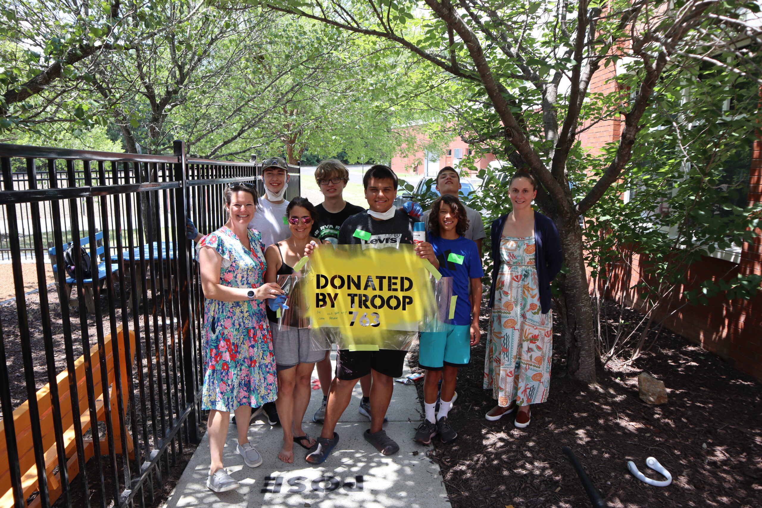 Boy Scout Troop 763 and /Northstar staff members pose with a used stencil on the sensory sidewalk.