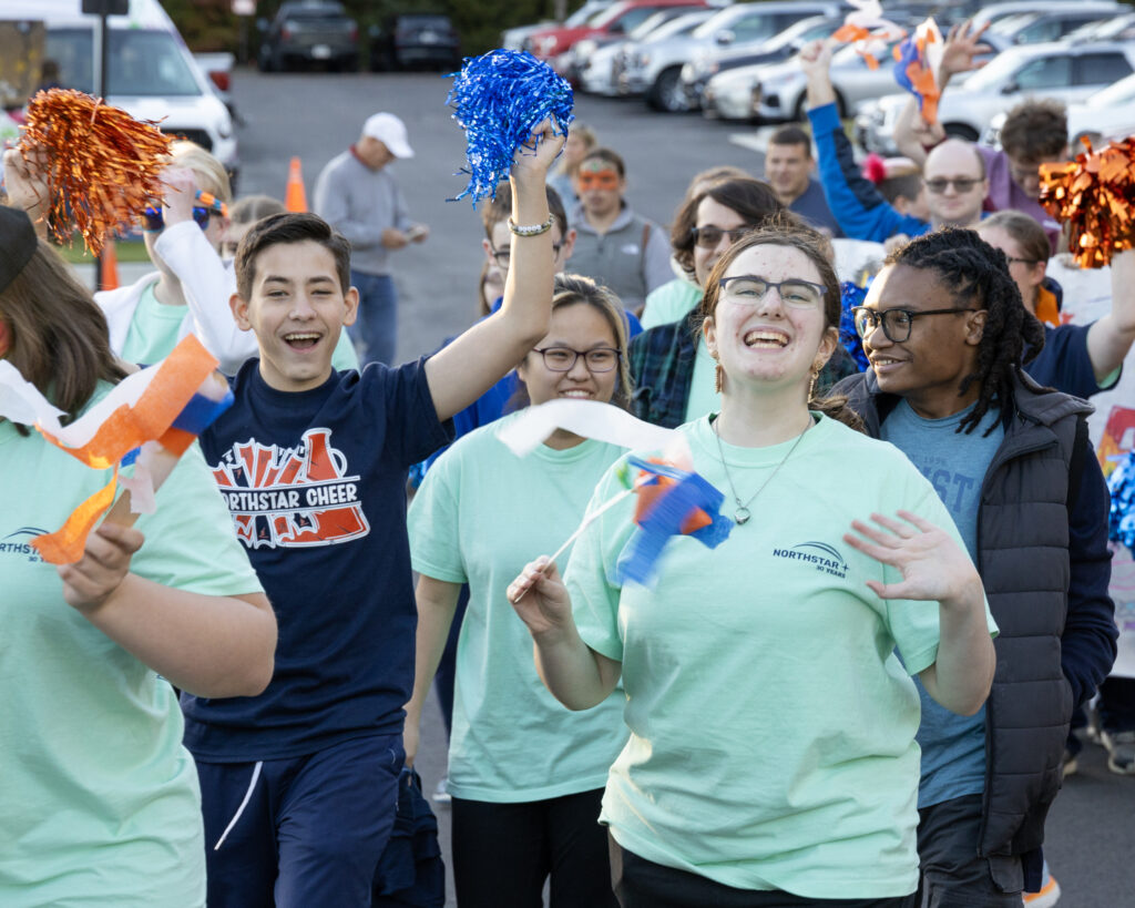 Homecoming Parade Smiles Students cheer and wave streamers as they walk with their peers in the parade at Northstar's Homecoming Celebration.