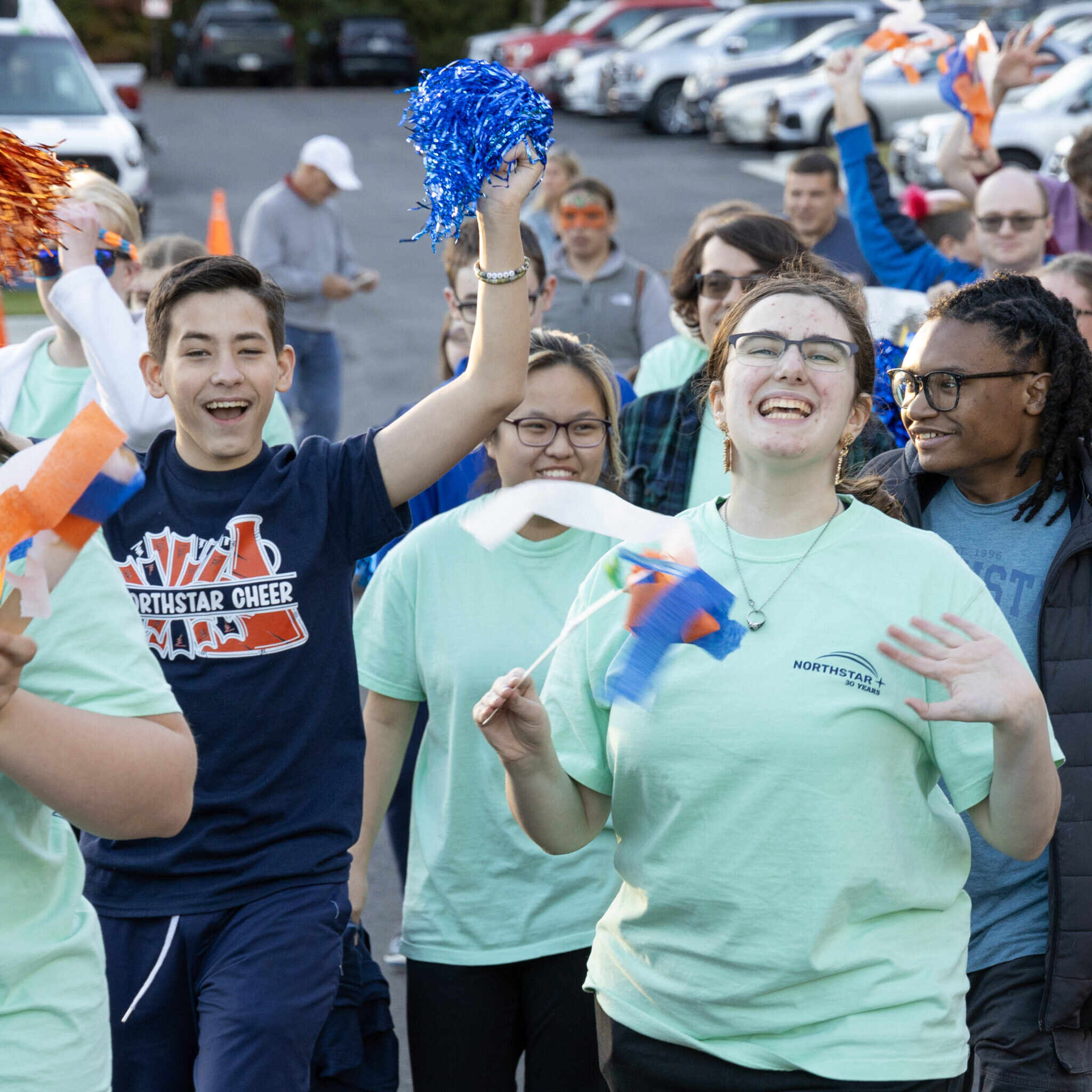Students cheer and wave streamers as they walk with their peers in the parade at Northstar's Homecoming Celebration.