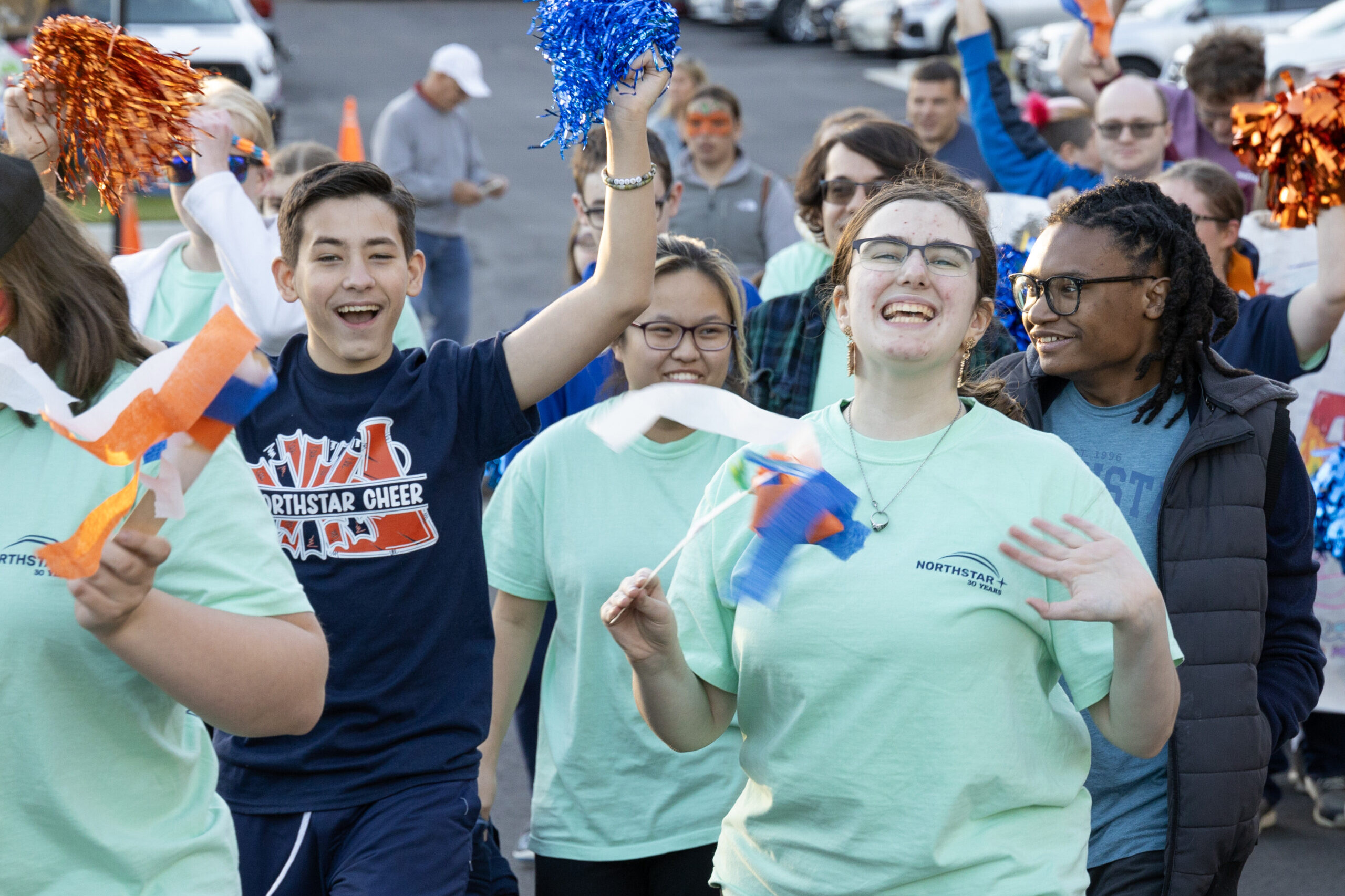Students cheer and wave streamers as they walk with their peers in the parade at Northstar's Homecoming Celebration.