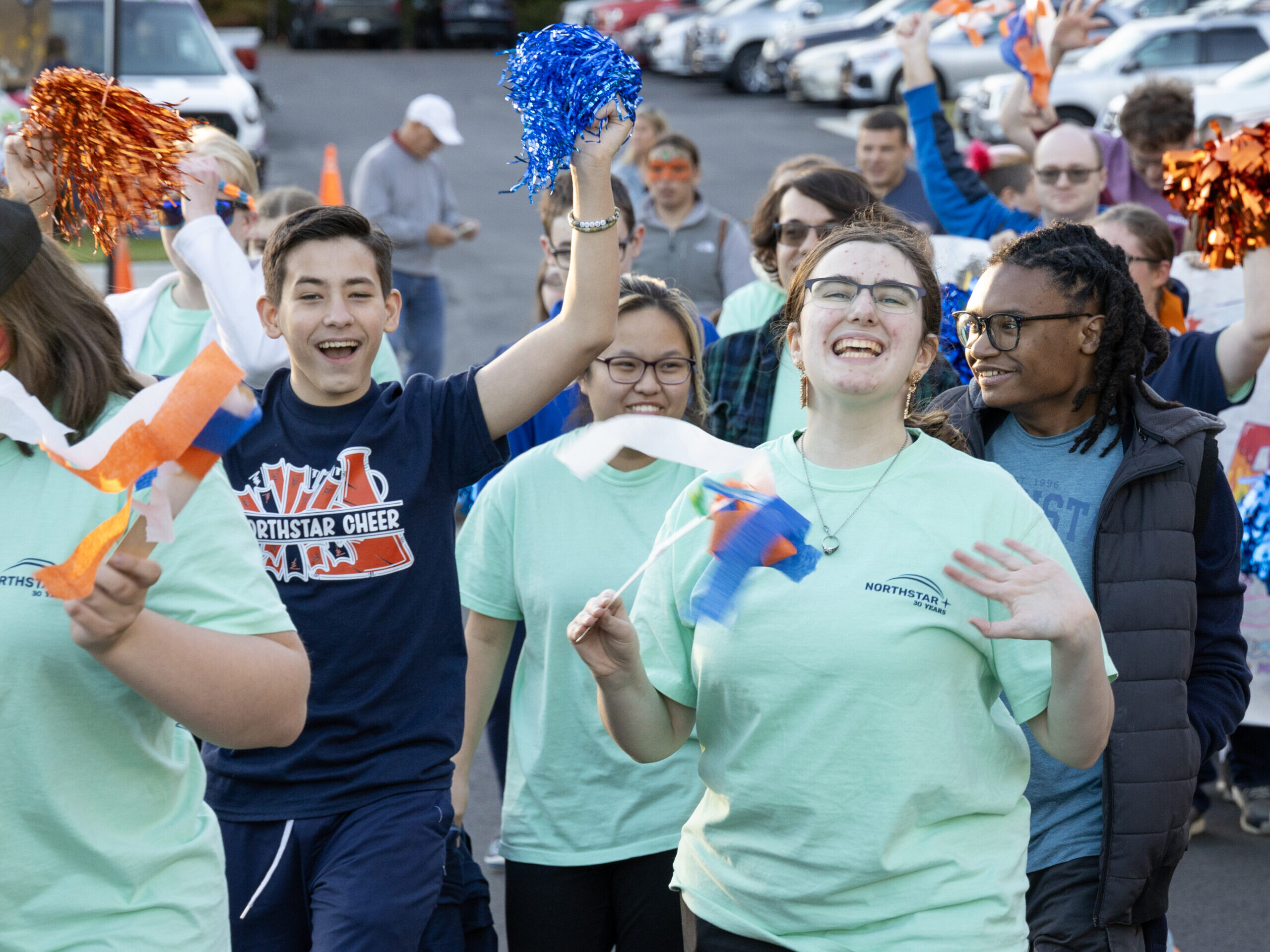 Students cheer and wave streamers as they walk with their peers in the parade at Northstar's Homecoming Celebration.
