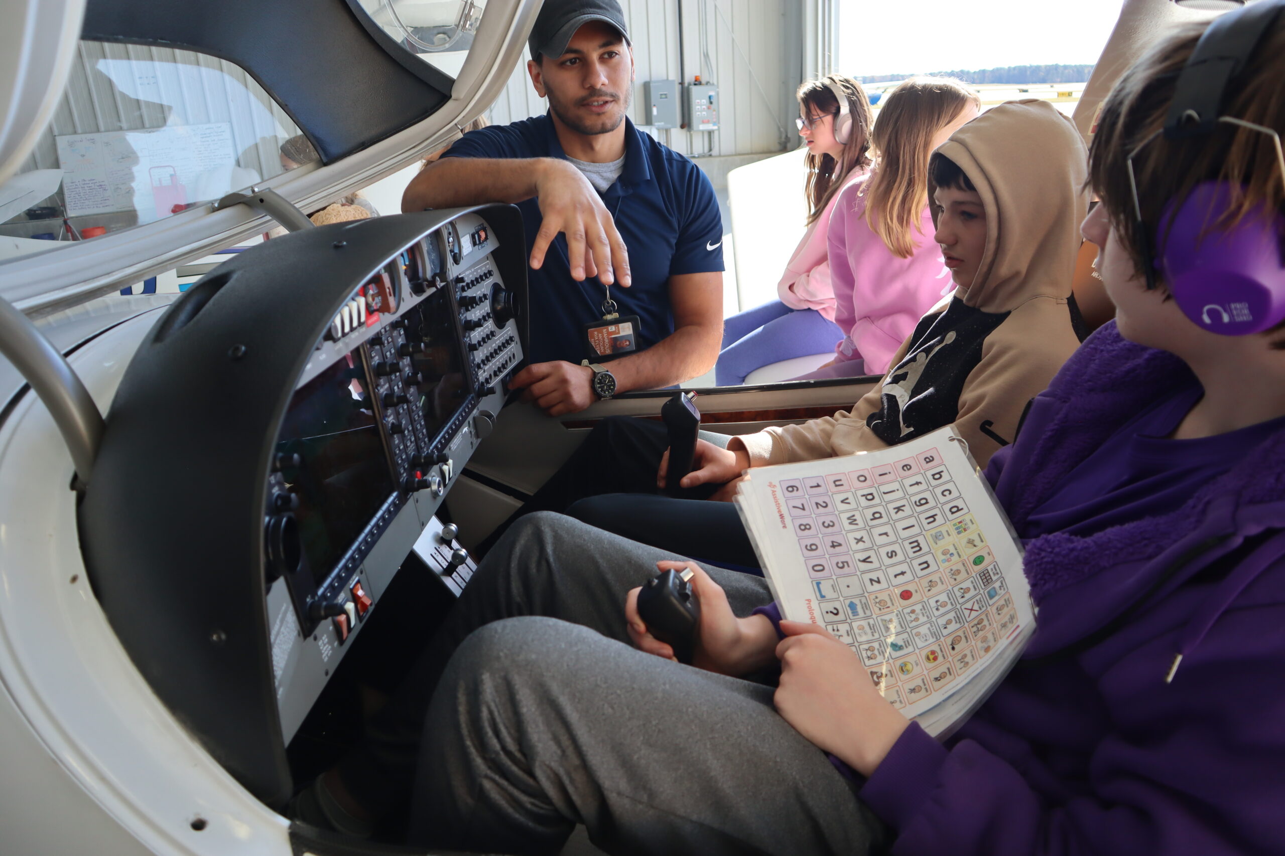 A flight instructor explains the controls to students as they sit inside an airplane.