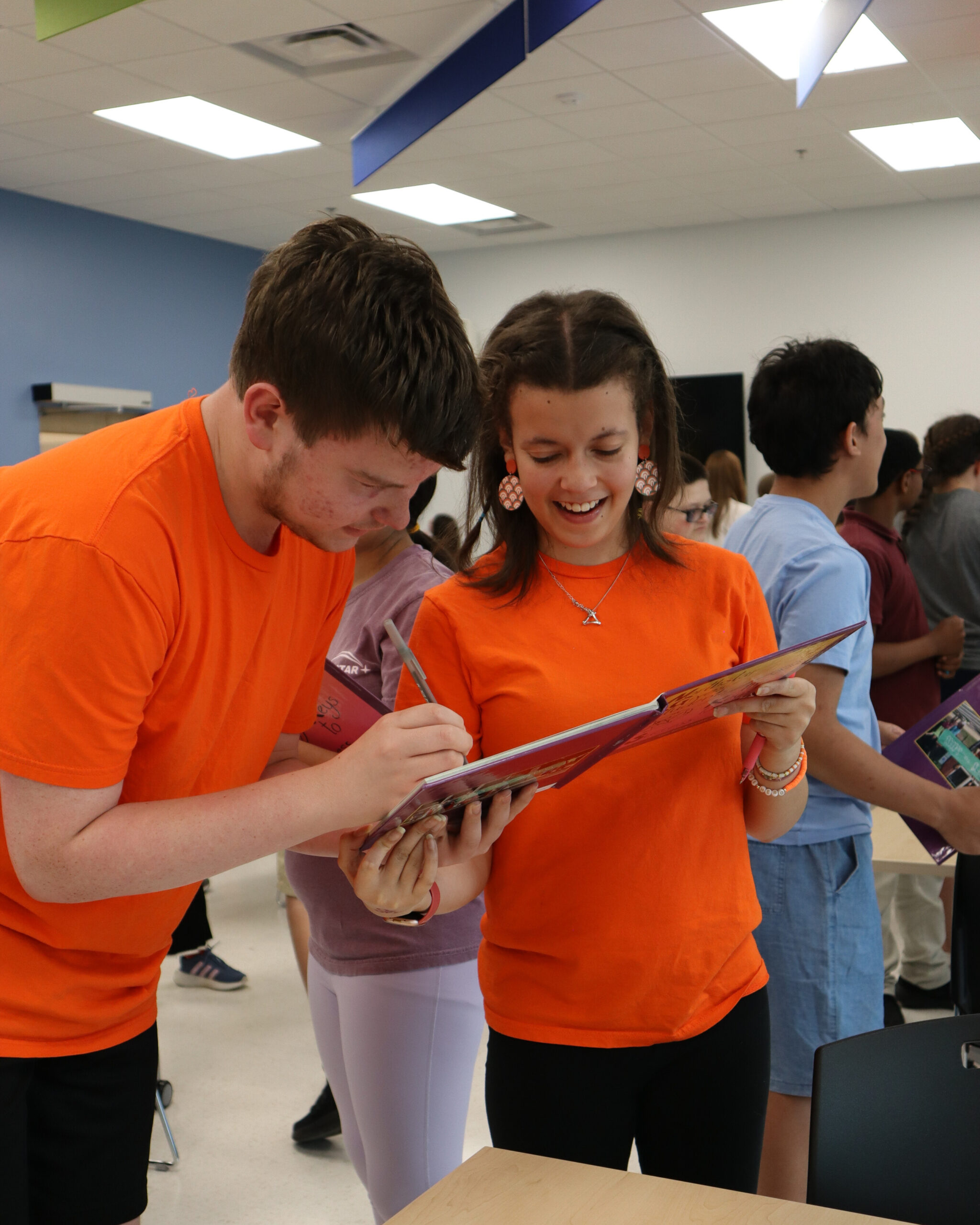 A student signs their peer's yearbook.