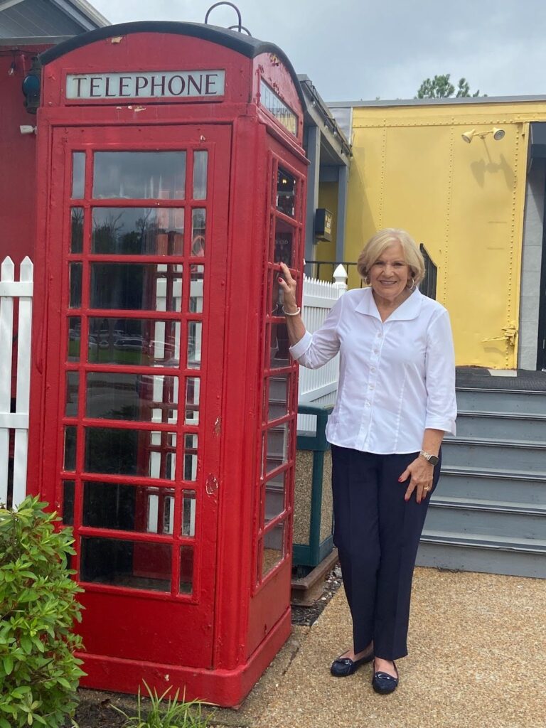 Donna Bower with red telephone booth Donna Bower stands with Northstar’s icon – the red telephone booth – during a 2025 visit to the former Shrader Road site.
