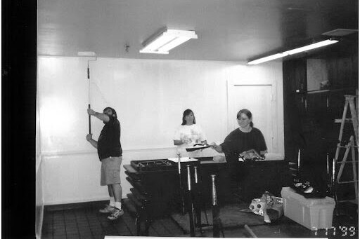 Black & white photo of parents painting train cars.