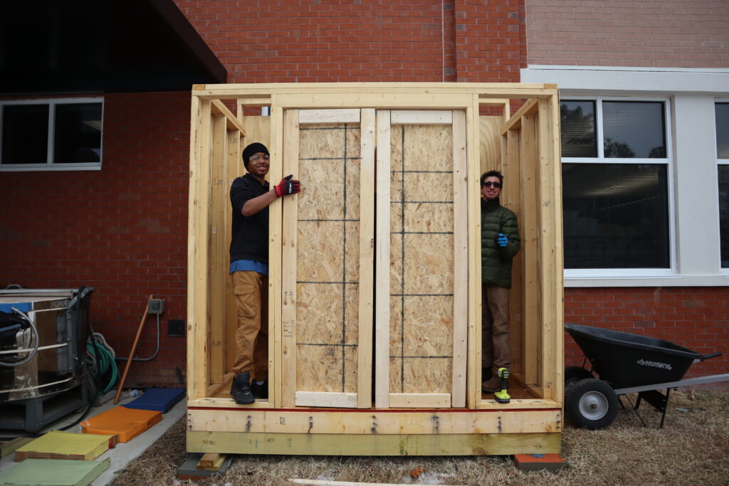 Shed building Two students secure walls to a half-built tool shed.