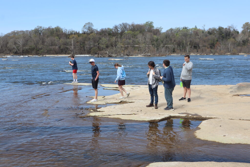 Students at the River A group of students stand on a large, flat rock on Belle Isle, overlooking Hollywood rapids.