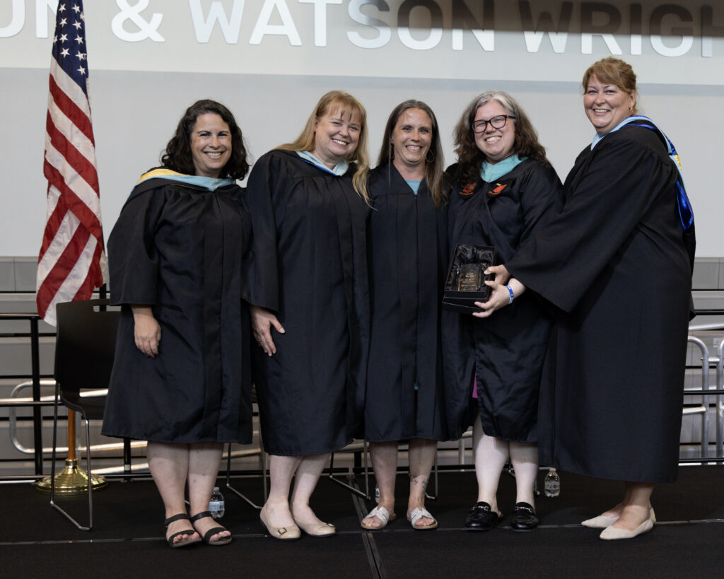 Surrounded by school leadership, Kristi Barbsy (middle) receives the Pat West Legacy Award in 2025 on stage.