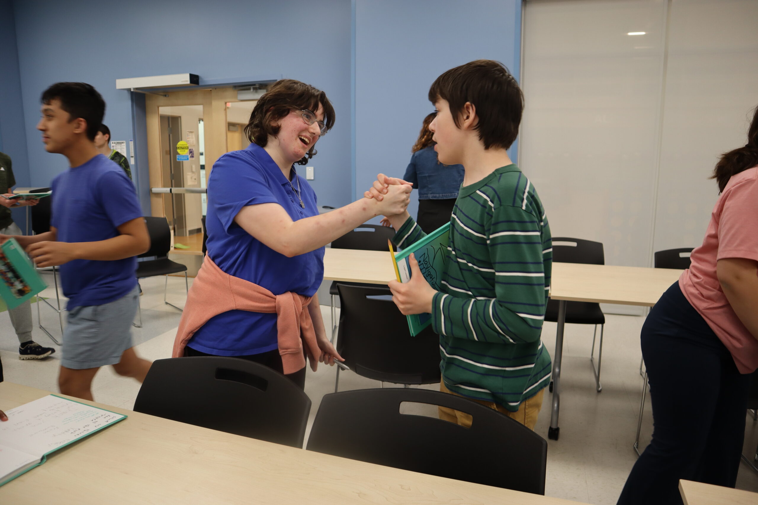Two students clasp hands in greeting in the Daly Family Community Room.